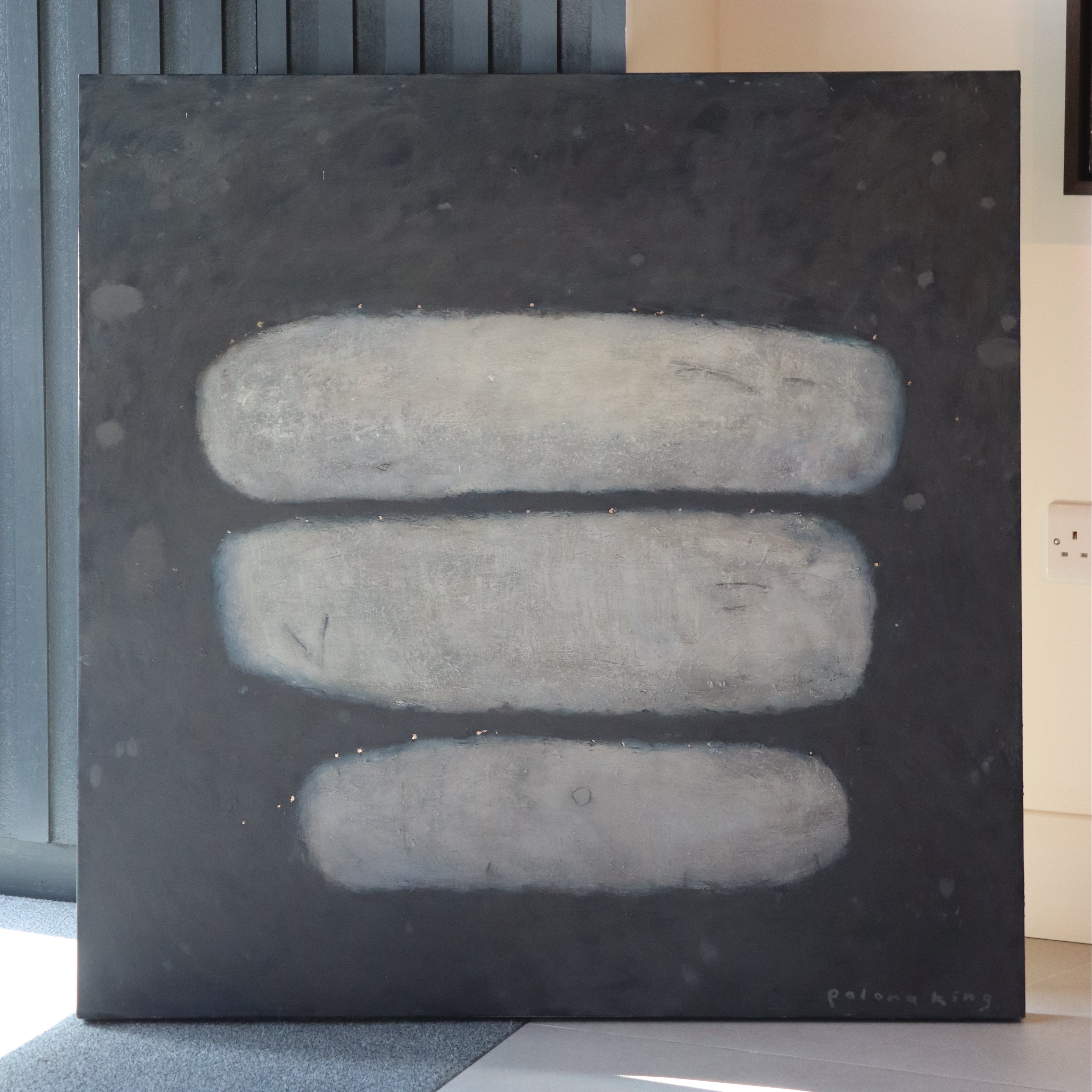 Three stone tablets on a black surface with a blurred indoor background